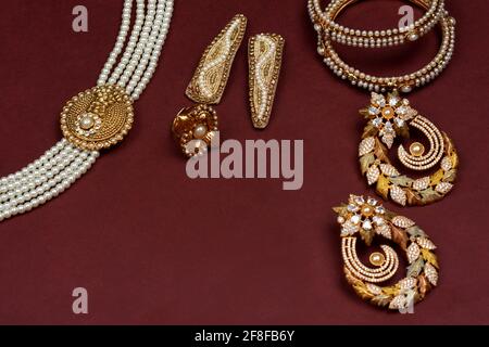 Perlenschmuck auf rotem Hintergrund, Goldener Schmuck, Perlenarmband, Perlenhaarclip, Perlenkette Perlenohrringe, Ring indischer traditioneller Schmuck Stockfoto