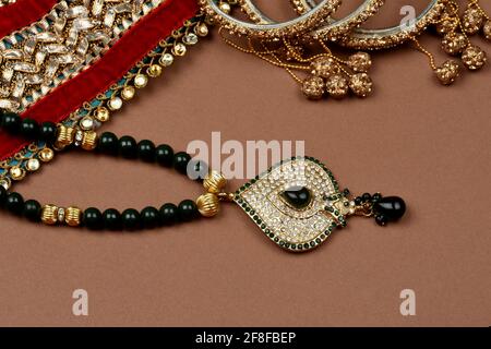 Antiker Schmuck auf braunem Hintergrund, goldener Schal, goldenes Armband, goldene Halskette, goldene Ohrringe, Fingerring indischer traditioneller Schmuck Stockfoto