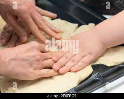 Kleiner Junge, der Pizza oder Brotteig knetet Stockfoto