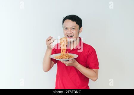 Porträt von glücklich junger asiatischer Mann genießt Nudeln. Essen Mittagessen Konzept. Stockfoto