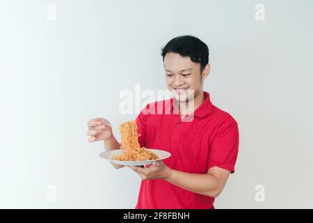 Porträt von glücklich junger asiatischer Mann genießt Nudeln. Essen Mittagessen Konzept. Stockfoto