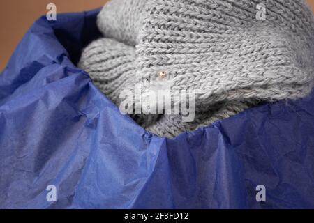 Makro matte transparente Anhänger auf einem grauen Strickschal in Eine schwarze Schachtel mit blauem Seidenpapier Stockfoto