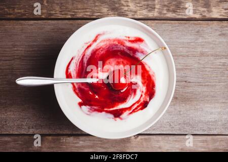 Kirschjoghurt in Schale auf rustikalem Holzhintergrund. Selektiver Fokus. Stockfoto