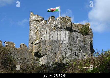 Walisische Flagge, die vom Schloss gegen den blauen Himmel fliegt - Manorbier East Tower Stockfoto