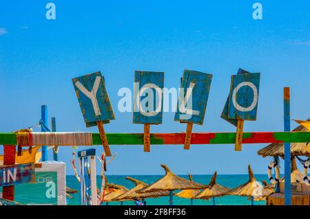 YOLO - Sie leben nur einmal - Zeichen auf Holz Bretter am Eingang zur Strandbar in der Nähe von The Black Meer an einem sonnigen Tag Stockfoto