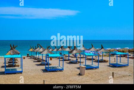 Strohschirme und Strandliegen an Sandstränden zum Sonnenbaden im Vama Veche Resort, Rumänien, Sonnenbaden im Sommer am Schwarzen Meer Stockfoto