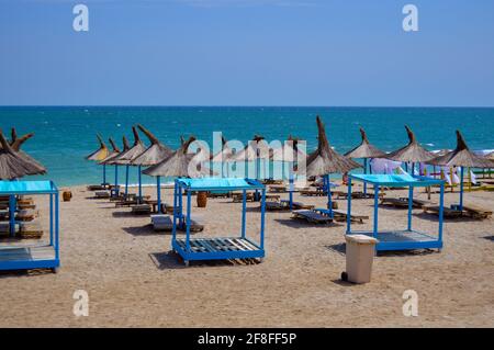 Strohschirme und Strandliegen an Sandstränden zum Sonnenbaden im Vama Veche Resort, Rumänien, Sonnenbaden im Sommer am Schwarzen Meer Stockfoto