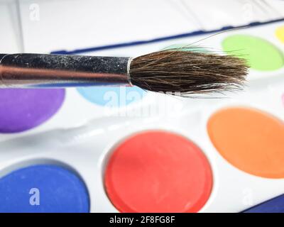 Den Pinsel und malt in den Farbkasten Stockfoto