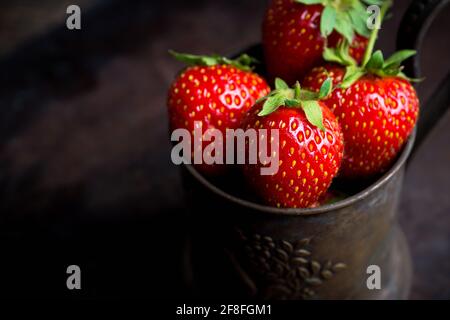 Reife und saftige Erdbeeren im alten rustikalen Metallbecher. Selektiver Fokus. Geringe Schärfentiefe. Stockfoto