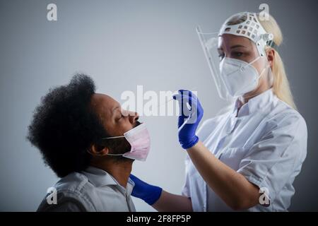 Krankenschwester, die PCR Covid-19-Test auf AFROAMERIKANISCHEN, weißen Hintergrund (CTK Photo/Vojtech Vlk) macht Stockfoto