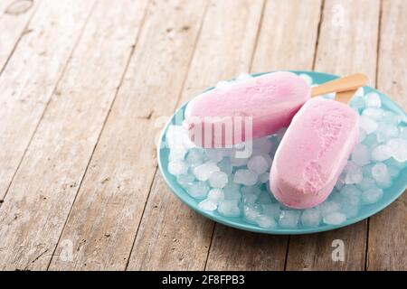 Erdbeerpopsicles und zerkleinertes Eis auf Holztisch Stockfoto