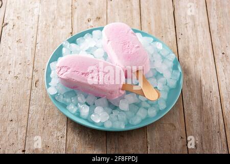 Erdbeerpopsicles und zerkleinertes Eis auf Holztisch Stockfoto
