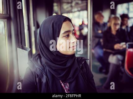 Mädchen aus dem Nahen Osten, die in der Stadt mit öffentlichen Verkehrsmitteln unterwegs sind Stockfoto