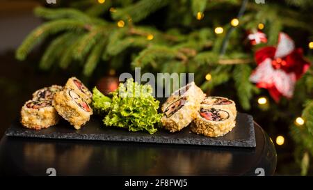 Benutzerdefinierte Sushi-Rolle in Tempura mit Nori, frischem Lachs, Thunfisch, Avocado, Masago-Kaviar, beträufelt mit Ananassauce mit Salat gießen als Dekoration auf Stockfoto