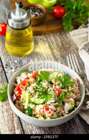 Essen Diät-Konzept, Thunfisch-Salat. Couscous-Salat mit konservierten Thunfisch, Tomaten, Gurken und lila Zwiebeln auf rustikalem Holztisch. Stockfoto