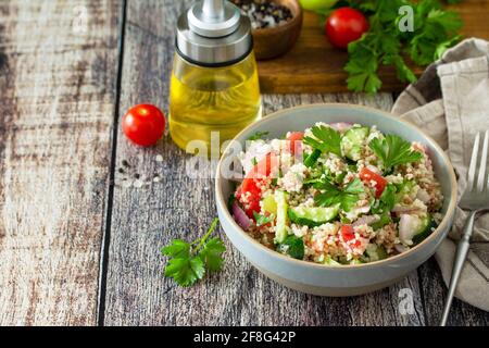 Essen Diät-Konzept, Thunfisch-Salat. Couscous-Salat mit konservierten Thunfisch, Tomaten, Gurken und lila Zwiebeln auf rustikalem Holztisch. Speicherplatz kopieren. Stockfoto