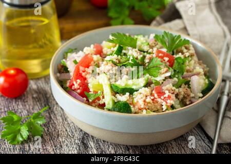 Diät-Konzept, Thunfisch-Salat aus der Nähe. Couscous-Salat mit konservierten Thunfisch, Tomaten, Gurken und lila Zwiebeln auf rustikalem Holztisch. Stockfoto