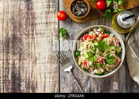 Essen Diät-Konzept, Thunfisch-Salat. Couscous-Salat mit konservierten Thunfisch, Tomaten, Gurken und lila Zwiebeln auf rustikalem Holztisch. Draufsicht flach liegend. Stockfoto