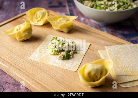 Faltanleitung für vegane Wontonknödel mit Tofu und Brokkoli auf Holzschneidebrett, Seitenansicht Stockfoto