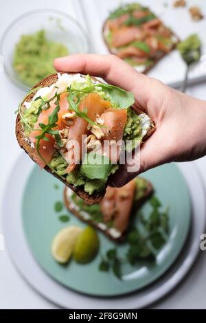 Gesunder Avocado-Toast mit Lachs und Käse auf weißem Hintergrund. Direkt darüber. Selektiver Fokus. Stockfoto