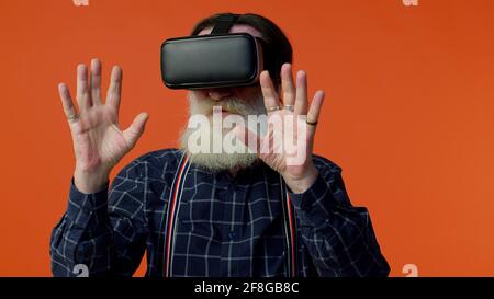 Ältere stilvolle grauhaarige Mann mit Headset Helm App zu spielen Simulation Virtual Reality VR-Spiel Stockfoto