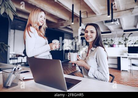 Zwei junge Kolleginnen trinken im Büro Kaffee Stockfoto