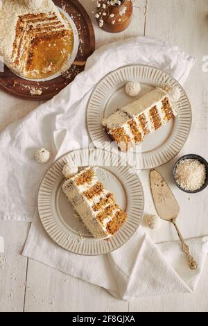 Draufsicht auf Scheiben von weißen cremigen Rafaello Kuchen mit Kugeln auf Platten Stockfoto