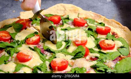 Pizza mit Käse, Tomaten, Spinat und Räucherwurst Stockfoto