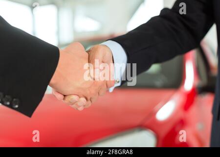 Zwei Männer in Anzügen Händeschütteln nach einem erfolgreichen Autokauf Stockfoto