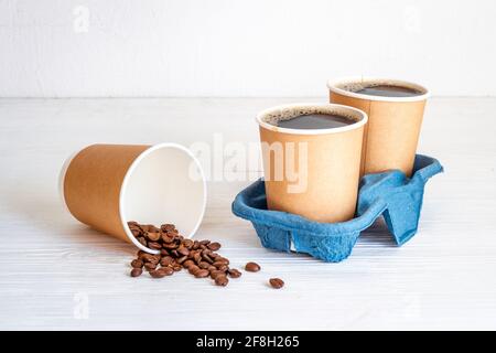 Schwarzer Kaffee in Pappbechern mit Bohnen. Nehmen Sie Kaffee Hintergrund Stockfoto
