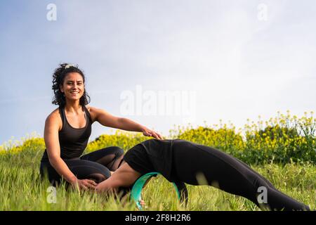 Yoga-Lehrer hilft Schüler durchführen Yoga-Übung in der Natur mit Die Hilfe eines Yoga-Elements Stockfoto