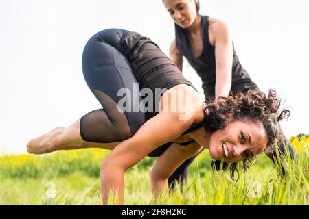 Mädchen tun schwierige Yoga-Position in der Natur, während sie Die Lehrerin lehrt sie Stockfoto