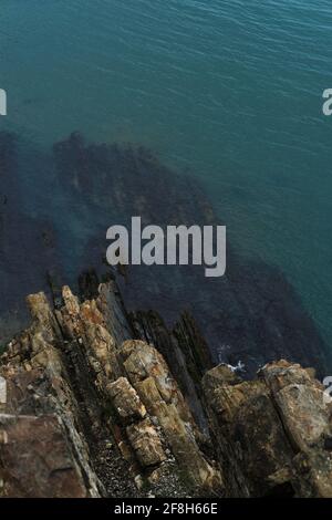 Blick von einer hohen Klippe auf das blau-türkisfarbene Meer und Korallenriffe unter dem Wasser. Wunderschöne schöne Seestücke von Drohne. Stockfoto