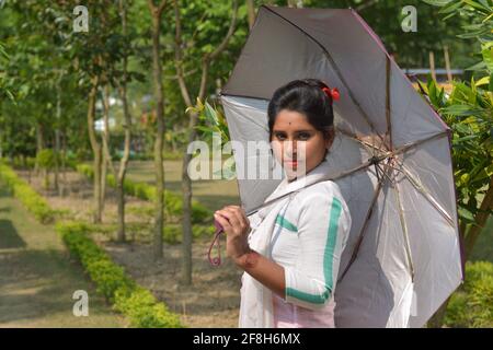 Teenage Indian Bengali Mädchen in weißen Baumwolle Salwar mit einem Regenschirm in einem Dorf Farm, selektive Fokussierung Stockfoto