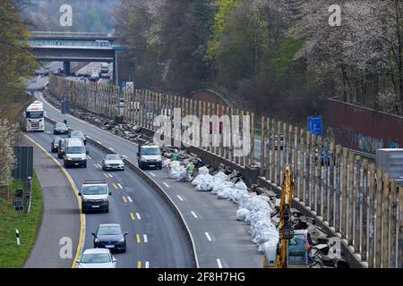 Sanierung Laermschutzwand auf der A52. Mehrere Arbeiter in Schutzangriffen und Atemmaske frachten den Inhalt von Schallschutzelementen in weisse SAE Stockfoto