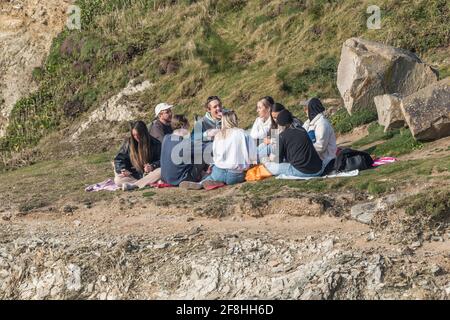 Eine Gruppe junger Leute, die zusammen sitzen und sich im Little Fistral in Newquay in Cornwall treffen. Stockfoto