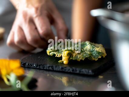 Hand des Mannes, der frittierte Speisen auf einem Schiefer mit Rücken zubereitete Leicht Stockfoto