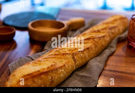 Langes Brot auf einer Holztheke mit weicher Struktur Stoffunterflecht Stockfoto