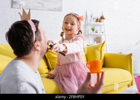 Glückliches Mädchen in Spielzeug Krone tun machen, um Vater auf Verschwommener Vordergrund Stockfoto