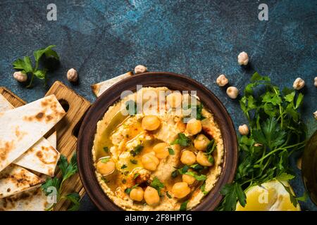 Hummus mit Olivenöl und Pita am Küchentisch. Stockfoto