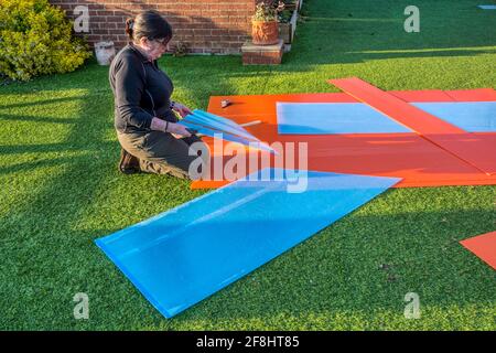 Frau schneidet Polycarbonat-Platten, um gebrochenes Glas im Gewächshaus zu ersetzen. Stockfoto