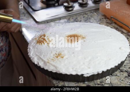 Schlagsahne von Key Limone Pie, verbrannt mit einer Lötlampe in der Küche. Süße Dessertzubereitung Stockfoto