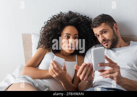 Schockiert interracial paar Blick auf Smartphone Stockfoto