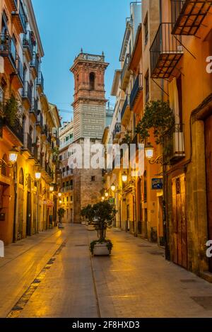 Blick bei Sonnenaufgang auf die Straße Carrer dels Serrans, die zum Torre de Sant Bartomeu Turm in Valencia, Spanien führt Stockfoto