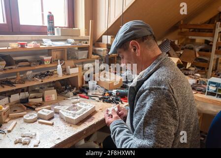 Gernrode, Deutschland. April 2021. Andreas Buchmann sitzt an einer Werkbank im Uhrmuseum Harz. Kuckucksuhren wurden früher im Unternehmen hergestellt. Heute werden solche Uhren fast ausschließlich repariert. Quelle: Stephan Schulz/dpa-Zentralbild/ZB/dpa/Alamy Live News Stockfoto