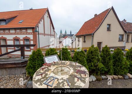 Gernrode, Deutschland. April 2021. Vor den Einfamilienhäusern steht eine Sonnenuhr. Dahinter sind die Türme der Stiftskirche St. Cyriakus zu sehen. In der Kirche befindet sich ein Grab aus dem 11. Jahrhundert. Es gilt als eine der ältesten Repliken des Jerusalemer Heiligen Grabes nördlich der Alpen. Quelle: Stephan Schulz/dpa-Zentralbild/ZB/dpa/Alamy Live News Stockfoto