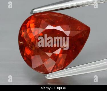Natürlicher Edelstein orange spessartine Granat auf grauem Hintergrund. Spessartite Granat Stockfoto
