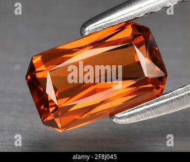 Natürlicher Edelstein orange spessartine Granat auf grauem Hintergrund. Spessartite Granat Stockfoto