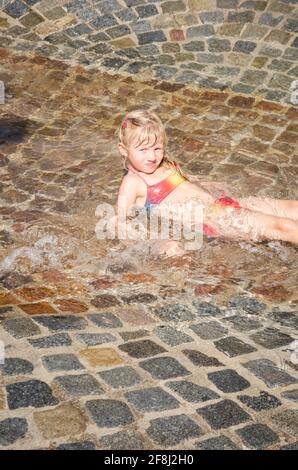 Kleines blondes Mädchen, das im Wasser spielt Stockfoto