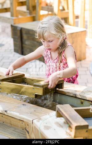 Liebenswert kleine blonde Mädchen Goldwaschen und versuchen, eine zu finden Gold Stockfoto